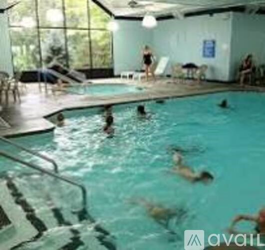 People are swimming in a pool with a diving board.