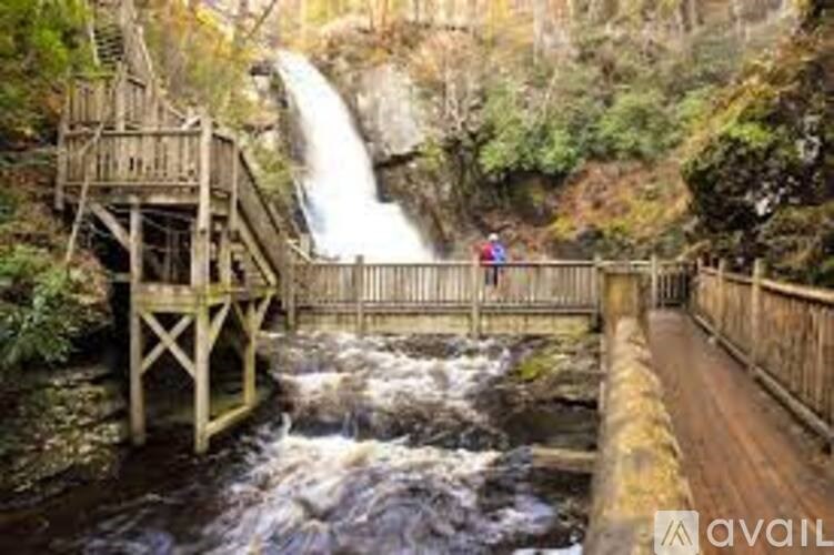 A wooden bridge over a fast flowing river with a waterfall in the background.