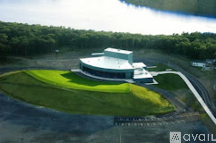 A modern building with a curved roof is surrounded by a grassy area.