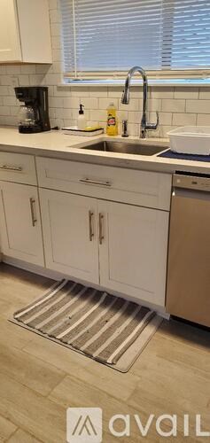 A kitchen with white cabinets and a striped rug on the floor.