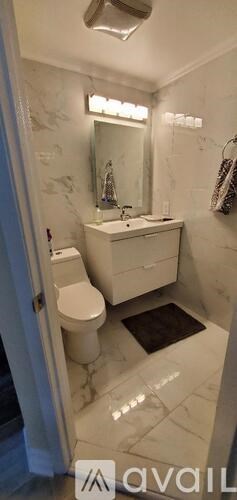 A bathroom with a toilet, sink, and mirror.