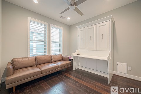 A living room with a brown leather couch and a white cabinet.