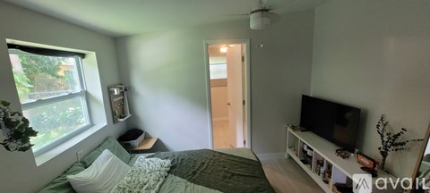 A bedroom with a bed, a television, and a window.