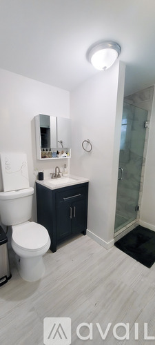 A bathroom with a toilet, sink, mirror, and a glass shower door.