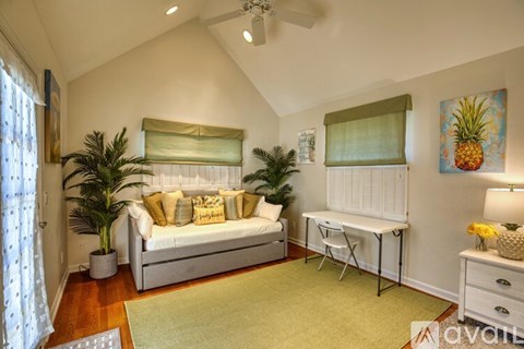 A living room with a couch, a table, and a painting of a pineapple.