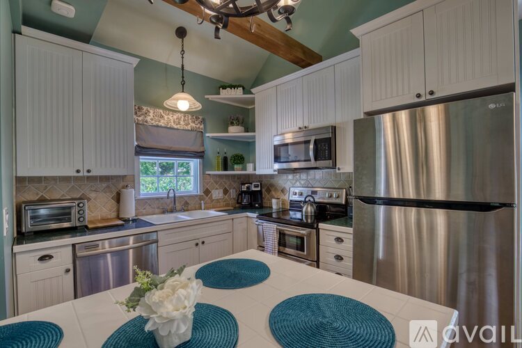A kitchen with a stainless steel refrigerator and a white table with a flower arrangement on it.