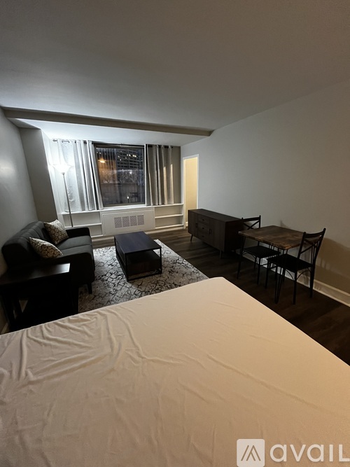 A bedroom with a large bed and a window with blinds.