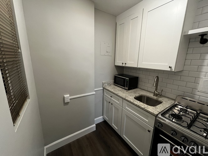 A kitchen with white cabinets and a stove top oven.