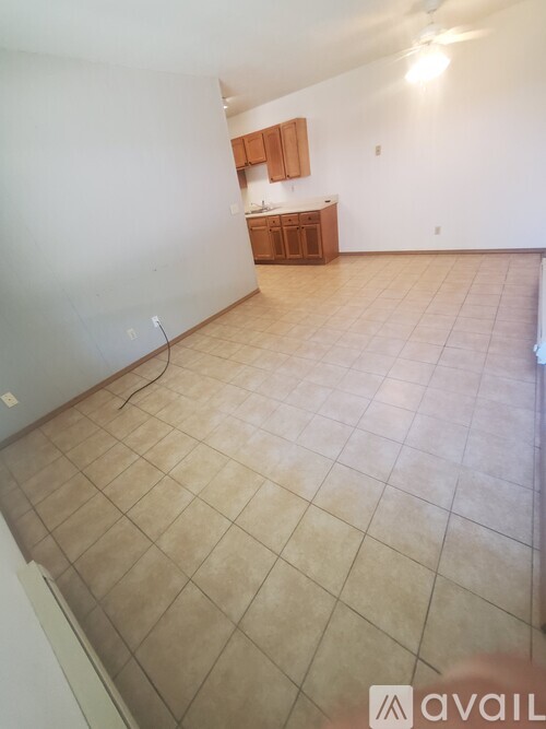 A room with tiled flooring and a small kitchenette.