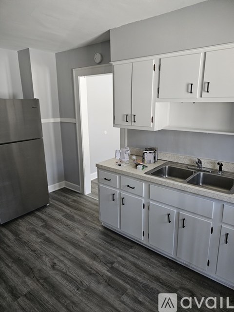 A kitchen with white cabinets and a grey refrigerator.