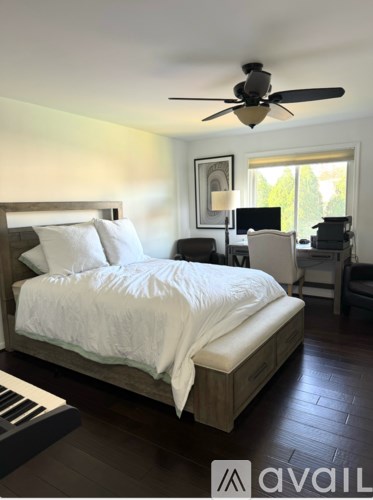 A bedroom with a large bed and a ceiling fan.