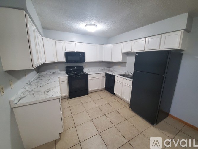 A kitchen with black appliances and white cabinets.