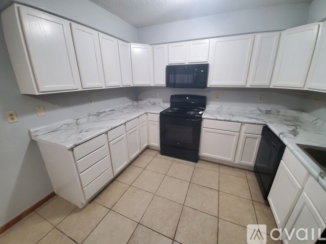 A kitchen with white cabinets and a black stove top oven.