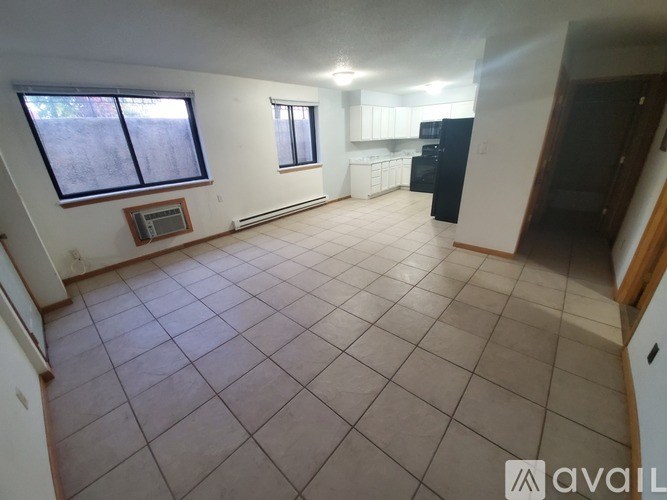 A living room with a tile floor and a refrigerator in the corner.