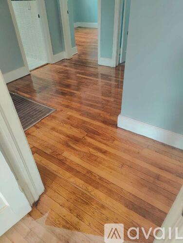 A hallway with wooden floors and white walls.