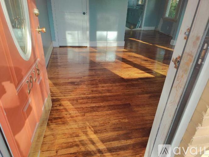 A hallway with wooden floors and a red door.