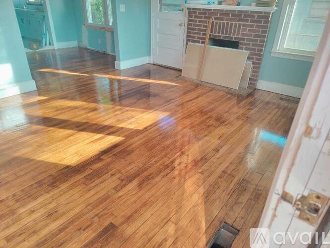 A room with wooden flooring and a brick fireplace.