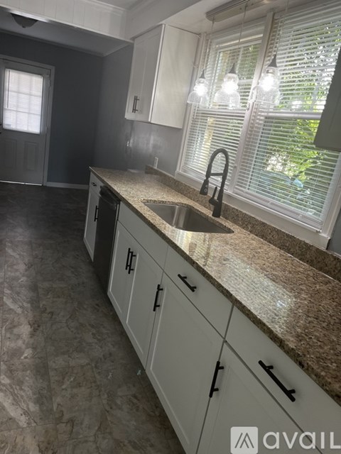 A kitchen with granite countertops and white cabinets.