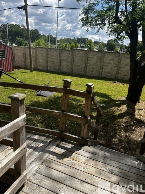 A wooden staircase leading to a grassy area with a fence in the background.