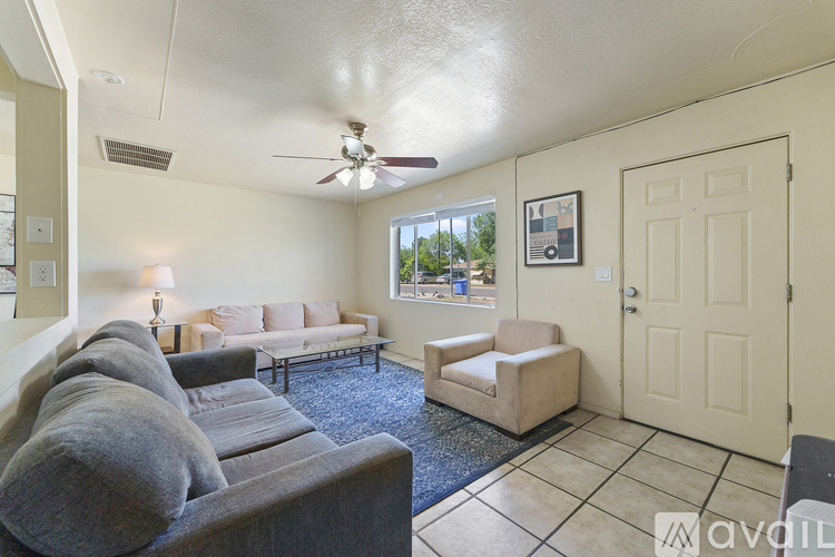 A living room with a grey couch and a fan on the ceiling.