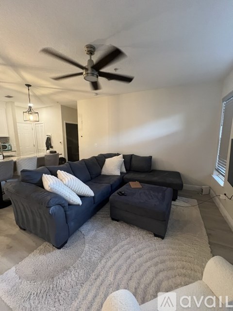 A living room with a dark blue couch and a white rug.