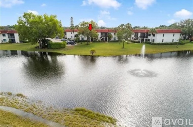A serene lake surrounded by buildings with a red arrow pointing to one of the buildings.
