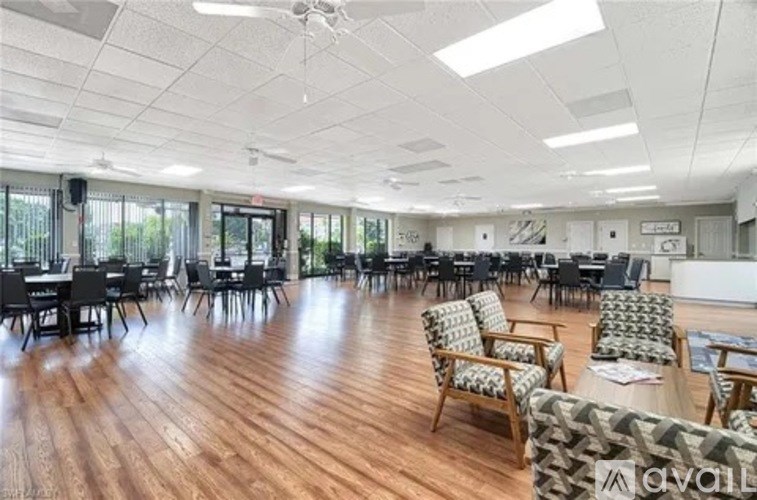 A spacious room with wooden floors and multiple chairs and tables.