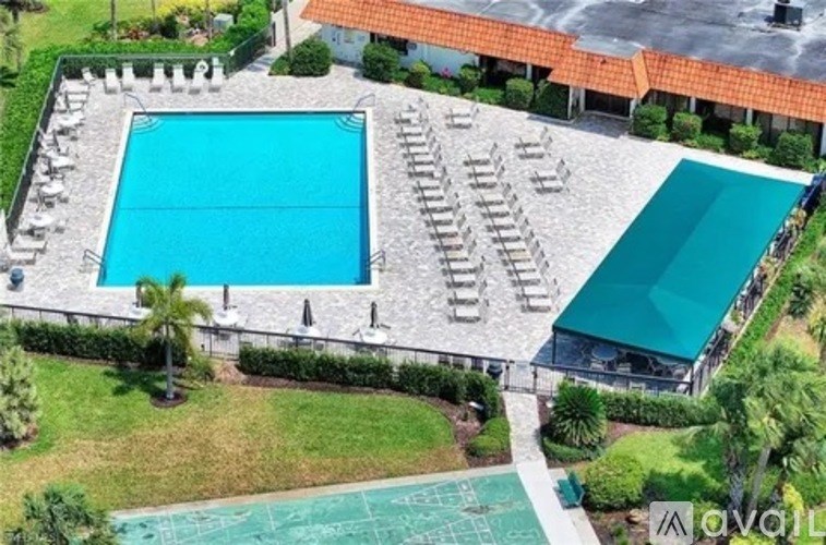 A large outdoor swimming pool surrounded by lounge chairs and greenery.