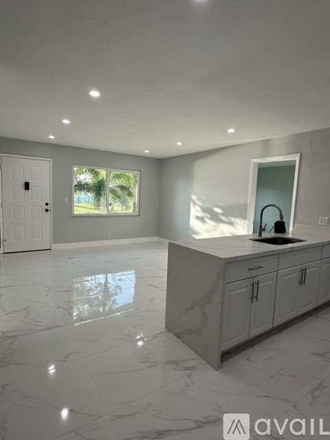 A kitchen with white cabinets and marble flooring.