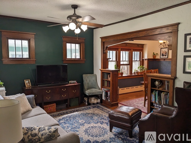 A living room with a television, a chair, a couch, and a rug.