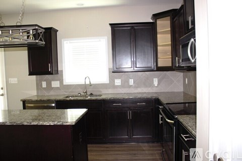 A kitchen with black cabinets and granite countertops.