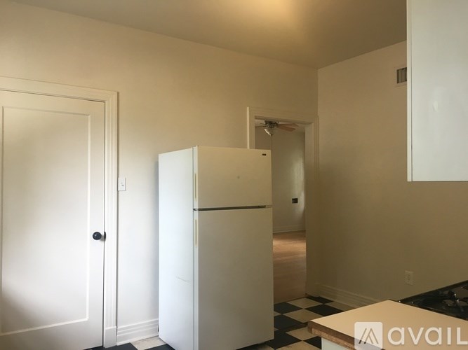 A white refrigerator in a room with a black and white checkered floor.