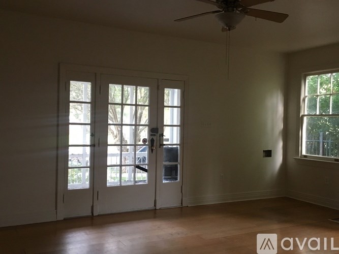 A room with a ceiling fan and a window with a view of trees.