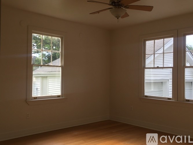 A room with a ceiling fan and two windows.