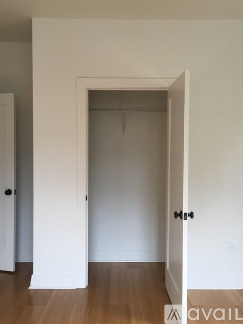 A white door with a black handle is open to a room with a wooden floor.