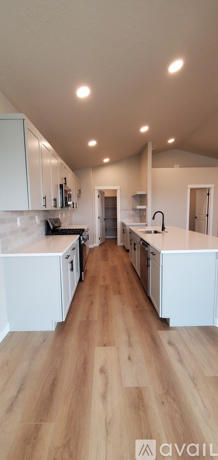 A kitchen with white cabinets and a wooden floor.