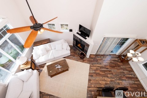 A living room with a white couch, a fan, and a fireplace.