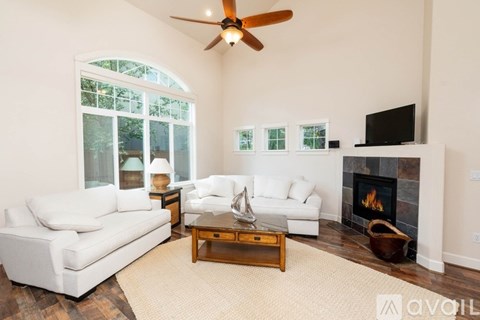 A living room with a white couch, a coffee table, and a fireplace.