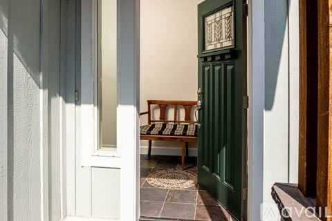 A green door with a wooden bench in front of it.