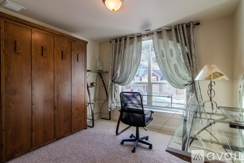 A room with a desk, chair, and a window with curtains.