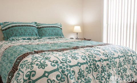 A bed with a teal and brown comforter and matching pillows.