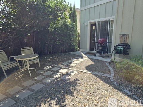A patio with a table and chairs is surrounded by trees.