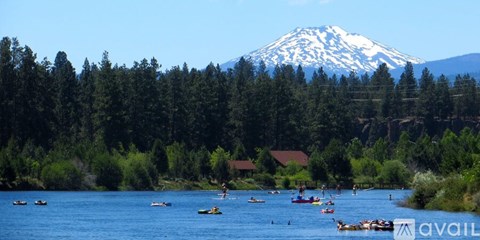 A group of people are kayaking on a river with a snow-capped mountain in the background.