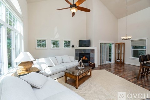 A living room with a white couch, a fireplace, and a ceiling fan.