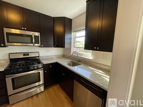 A kitchen with black cabinets and a stainless steel oven.