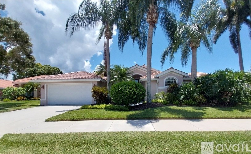 A house with a driveway and palm trees in front.