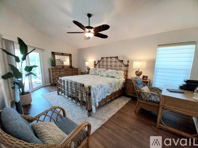 A bedroom with a bed, chair, and a ceiling fan.