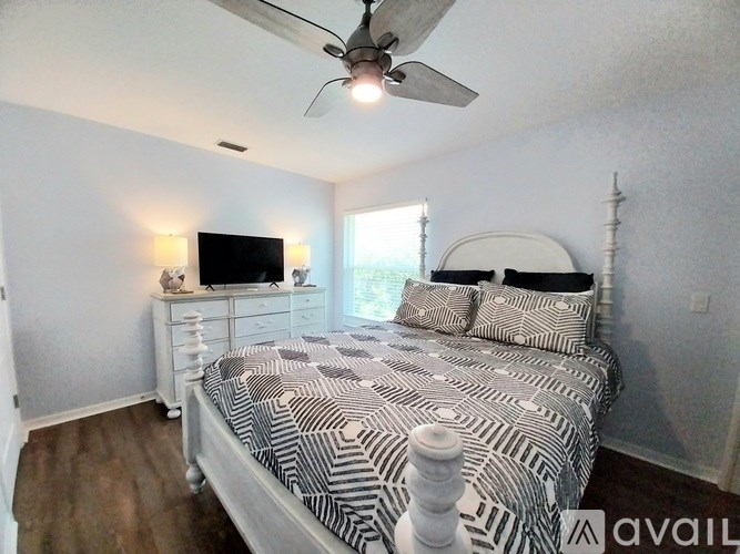A bedroom with a bed, dresser, and television.