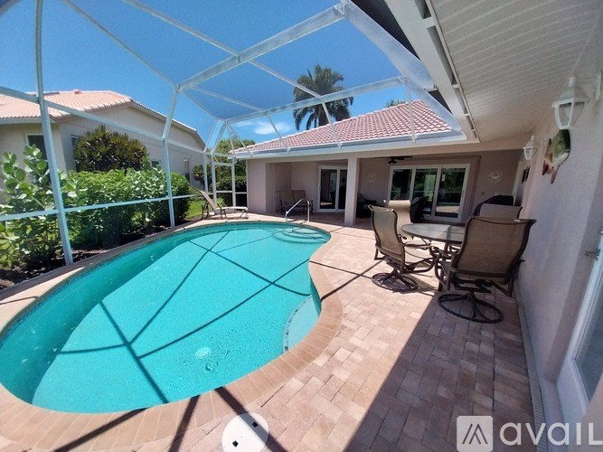 A pool with a glass table and chairs under a white awning.