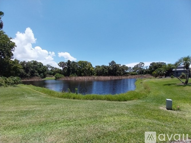 A grassy field with a lake and trees in the distance.